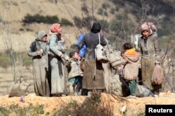 Internally displaced people, covered with mud, wait as they are stuck in the town of Khirbet al-Joz, in Latakia countryside, waiting to get permission to cross into Turkey near the Syrian-Turkish border, Syria, Feb. 7, 2016.