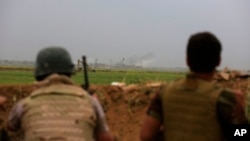 FILE - Smoke rises from positions in the IS-held town of Besher, during a military operation to regain control of the small town, outside the oil-rich city of Kirkuk, 180 miles (290 kilometers) north of Baghdad, Iraq, April 10, 2016.