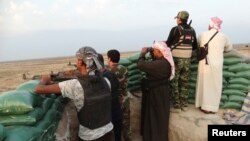 Pejuang dari suku di Irak membawa senjata dalam pertempuran dengan ISIS di kota Amriyat al-Falluja, provinsi Anbar (31/10). 