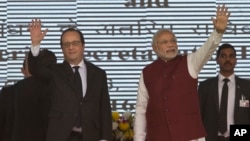 French President Francois Hollande, left, and Indian Prime Minister Narendra Modi wave at the audience as they arrive for the foundation stone laying for the headquarters of the International Solar Allliance at Gurgaon, outskirts of New Delhi, Jan. 25, 2016.