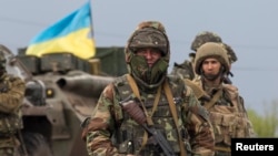 A Ukrainian soldier stands guard near an armoured personnel carrier at a checkpoint near Slovyansk, eastern Ukraine, on May 2, 2014. 