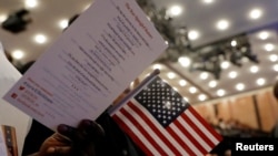 FILE - New citizens stand during a U.S. Citizenship and Immigration Services (USCIS) naturalization ceremony in Manhattan, New York, April 10, 2017. Three men were accused Tuesday of abusing a U.S. visa program and making false statements to the USCIS.