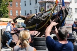 Crews lower the statue of Confederate General J.E.B. Stuart in preparation for transport after removing it from it's pedestal on Monument Avenue in Richmond, Va., July 7, 2020.