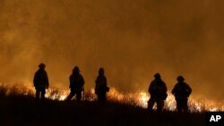 Firefighters stand guard as flames from the Butte Fire approach a containment line in San Andreas, California, Sept. 12, 2015.