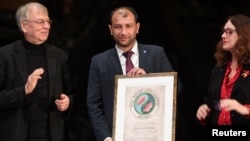 Raed al-Saleh (C), head of the Syria Civil Defense 'White Helmets', receives the Right Livelihood Award prize from Jakob von Uexkull (L), the founder of the award, during a ceremony at the Vasa Museum in Stockholm, Sweden, Nov. 25, 2016.