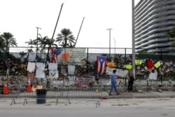 A man walks past a makeshift memorial site as search and rescue efforts resume the day after the managed demolition of the remaining part of Champlain Towers South complex, in Surfside, Florida, July 5, 2021.