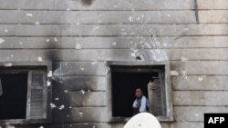 Free Syrian Army fighter looks out from the window of the burnt Shaar district police station in the northern Syrian city of Aleppo after it was overrun by rebel fighters on July 25, 2012. 