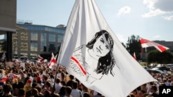 People hold a flag with a portrait of Sviatlana Tsikhanouskaya, former candidate for the presidential elections, during a rally in Minsk, Belarus, Aug. 17, 2020.