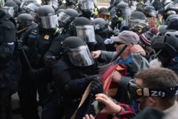 FILE - Capitol Police in riot gear push back demonstrators trying to break a door of the U.S. Capitol, Jan. 6, 2021.