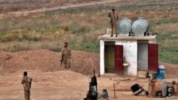 FILE- Fighters from the Syrian Democratic Forces stand guard at the Syrian side of the border with Iraq near Rabiaa border crossing, Iraq, Oct. 16, 2019.