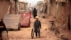 FILE - A boy plays with a tire on an a street in an Afghan refugee camp in Islamabad, Pakistan, Oct. 31, 2017. 