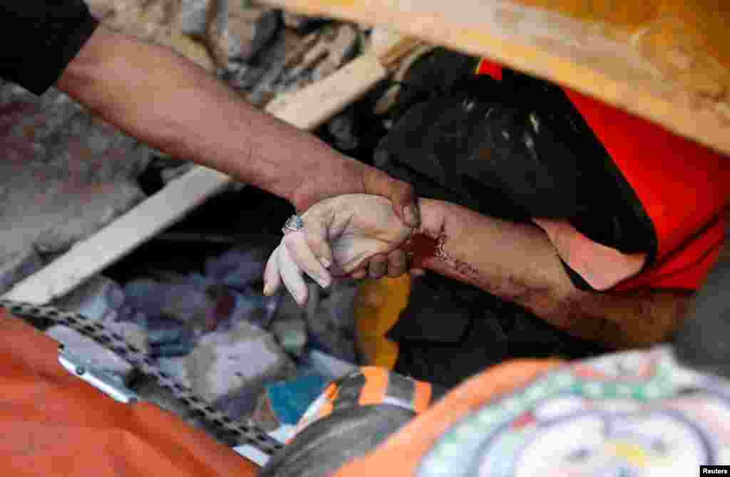 Un rescatista sostiene la mano de una víctima entre los escombros en el lugar de los ataques aéreos israelíes, en la ciudad de Gaza.