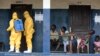 Residents of a West African village watch as members of a response team disinfect an area as they pick up suspected Ebola patients that had been quarantined, Sept. 30, 2014.