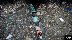 FILE - A worker collects garbage from the Marilao River in Bulacan, north of Manila, on March 18, 2017. 