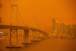 The San Francisco Bay Bridge and city skyline are obscured in orange smoke and haze as seen from Treasure Island in San Francisco, California, Sep. 9, 2020.