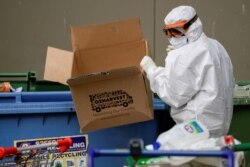 FILE - A worker in personal protective equipment disposes of rubbish outside a public housing tower, reopened the previous night after being locked down in response to an outbreak of the coronavirus disease, in Melbourne, Australia, July 10, 2020.