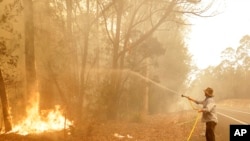A man battles a fire near Moruya, Australia, Jan. 4, 2020. Australia's Prime Minister Scott Morrison called up about 3,000 reservists as the threat of wildfires escalated Saturday in at least three states.