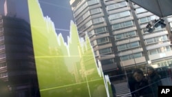 Pedestrians are reflected in an electronic stock chart showing Japan's Nikkei 225 at a securities firm in Tokyo, Tuesday, Feb. 9, 2016.