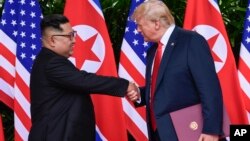 Pemimpin Korea Utara Kim Jong Un dan Presiden AS Donald Trump dalam pertemuan pertama di Singapura, 12 Juni 2018 - atau tepat setahun lalu (foto: dok). 