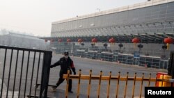 一名保安人员星期天1月26日正在北京四惠长途车站关上铁门。