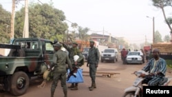 Soldiers gesture in front of La Terrasse restaurant where militants killed five people, including a French citizen and a Belgian citizen, in a gun attack in Bamako, March 7, 2015. 