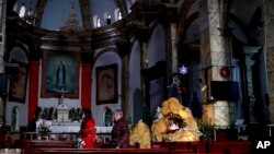 FILE - Chinese women walk past a decoration displaying a Baby Jesus doll part of a Nativity scene, at the Nantang Catholic Church in Beijing. Last month the Chinese government’s head of religious affairs told a meeting of the official Catholic Church in the vast Communist country that he hoped the Vatican would try to improve relations by adapting to his society. 