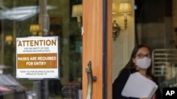 FILE - A sign reminds customers to wear masks at a bakery in Lake Oswego, Oregon, May 21, 2021. Oregon Gov. Kate Brown on Aug. 10 announced a statewide indoor mask requirement due to the spike in COVID-19 hospitalizations and cases.