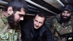 FILE - Syrian President Bashar al-Assad, center, speaks with Syrian troops during his visit to the front line in the eastern Damascus district of Jobar, Dec. 31, 2014.