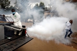 A man walks through smoke generated by Nairobi municipality worker in an effort to fight against the spread of the coronavirus disease (COVID-19) in the Kawangware neighborhood of Nairobi, Kenya, May 2, 2020.