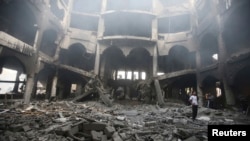 A Palestinian looks at the remains of a commercial center, which witnesses said was hit by an Israeli airstrike on Saturday, in Rafah in the southern Gaza Strip, Aug. 24, 2014. 