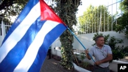 A man waves a Cuban flag while celebrating the restoration of diplomatic relations between Havana and Washington, in the courtyard of the Cuban Embassy in Santiago, Chile, Dec. 17, 2014.