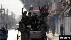 Turkey-backed Syrian rebel fighters gesture as they stand on the back of a truck in the border town of Tal Abyad, Syria, Oct. 17, 2019. 