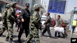 FILE - Armed Chinese paramilitary policemen march past the site of an explosion outside the Urumqi South Railway Station in Urumqi in northwest China's Xinjiang Uygur Autonomous Region.