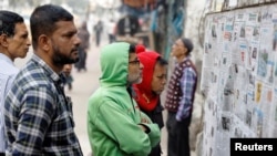 People read pages of newspapers stuck on a wall, the morning after Bangladesh Awami League won the 12th general election, in Dhaka