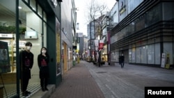 FILE - Shopkeepers wearing masks to prevent contracting the coronavirus wait for a customer at Dongseong-ro shopping street in central Daegu, South Korea, Feb. 21, 2020.