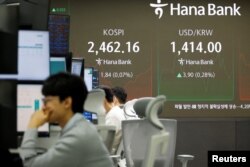 Para pedagang valuta sedang bekerja di depan papan elektronik yang menunjukkan Indeks Harga Saham Gabungan Korea (Kospi) di sebuah bank di Seoul, Korea Selatan, Kamis, 5 Desember 2024. (Foto: Kim Soo-hyeon/Reuters)
