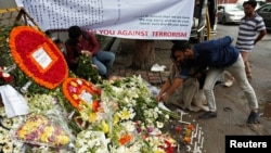 People place flowers at a makeshift memorial near the site, to pay tribute to the victims of the attack on the Holey Artisan Bakery and the O'Kitchen Restaurant, in Dhaka, Bangladesh, July 5, 2016.