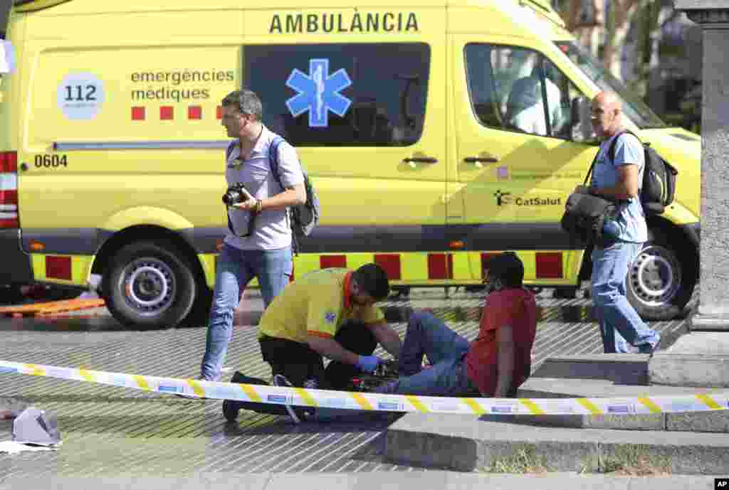 An injured person is treated in Barcelona, Spain, Aug. 17, 2017 after a white van jumped the sidewalk in the historic Las Ramblas district, crashing into a summer crowd of residents and tourists.