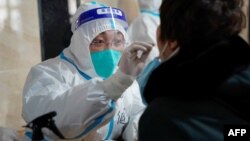 中国哈尔滨一位医疗人员在进行新冠检测采样 （法新社 2021年1月14日）