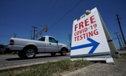 FILE - A pick-up truck passes a sign for free COVID-19 testing, in San Antonio, Texas, Aug. 14, 2020.