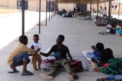 After fleeing the war in Libya, these families who also fled war, genocide and other violence in Sudan and Eritrea shelter under an awning in a parking lot, with nowhere else to go, July 5, 2019, in Tripoli, Libya. (Heather Murdock/VOA)