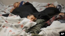 FILE - This June 18, 2014, file photo shows children detainees sleeping in a holding cell at a U.S. Customs and Border Protection processing facility in Brownsville, Texas. 