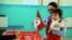 FILE - A woman casts her vote with her child during the first round of the Tunisian presidential election in a polling station at Marsa, outside Tunis, Nov. 23, 2014. The vote was another step forward in Tunisia's peaceful transition to democracy.