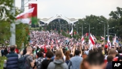 Belarusian opposition supporters with old Belarusian national flags gather toward the Independence Palace, the residential of Belarusian President Alexander Lukashenko in Minsk, Belarus, Sept. 6, 2020.