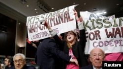 FILE - Code Pink demonstrators surround former U.S. Secretaries of State Henry Kissinger and George Shultz before the beginning of the Senate Armed Services Committee on global challenges and U.S. national security strategy on Capitol Hill in Washington Jan. 29, 2015.