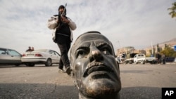 Боєць опозиції біля поваленого пам'ятника Хафезу Асаду в Дамаску, 8 грудня 2024 року