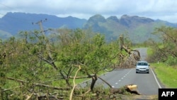 This undated handout photograph released on Feb. 22, 2016, by the Fiji government shows a car driving past uprooted trees following Cyclone Winston in Fiji's western division.