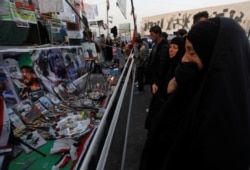 FILE - An Iraqi woman reacts as she looks at a makeshift memorial with personal belongings of those who were killed at anti-government protests at Tahrir Square in Baghdad, Iraq, Nov. 23, 2019.