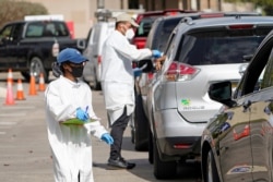 In this Nov. 19, 2020, file photo, healthcare workers process people waiting in line at a United Memorial Medical Center COVID-19 testing site in Houston.