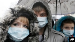 FILE - Ukrainians wearing medical masks demonstrate in front of the memorial monument to AIDS victims in Kyiv, Ukraine.